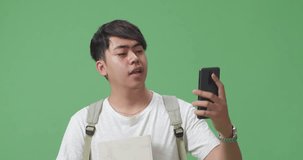 Close Up Of Asian Man Student Having Video Call By Mobile Phone On Green Screen Studio
