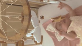 Vertical video. Top view of baby girl crying while lying in the crib in nursery, selective focus