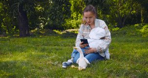 Young mother with a child during a walk outdoors - mom watches a video through an online application for a smartphone while the child sleeps. 4k footage.
