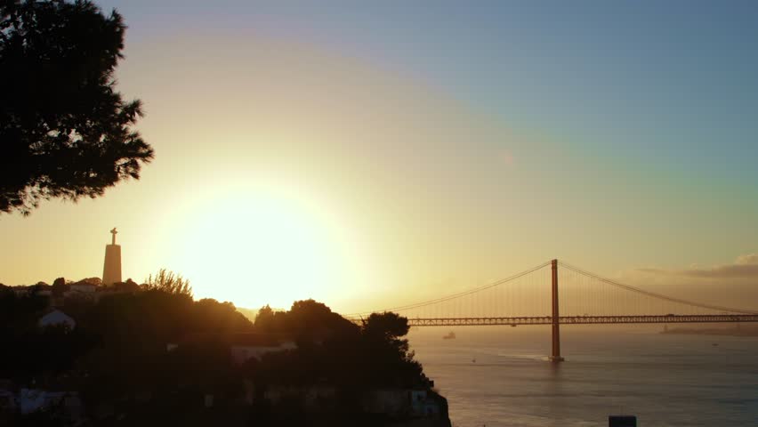 Sun going down above the river and a suspension bridge