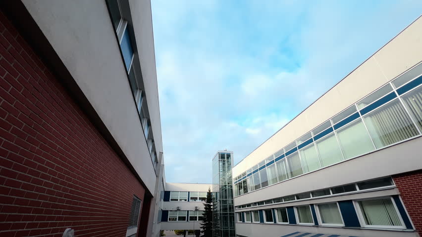 Wide angle: Modern hospital building with glass windows and an elevator over blue sky