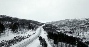 European E8 route crossing snowy rural landscape, northern Norway. Aerial drone panoramic view. Sky for copy space