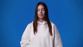 4k slow motion video of one girl showing thumb down on blue background.