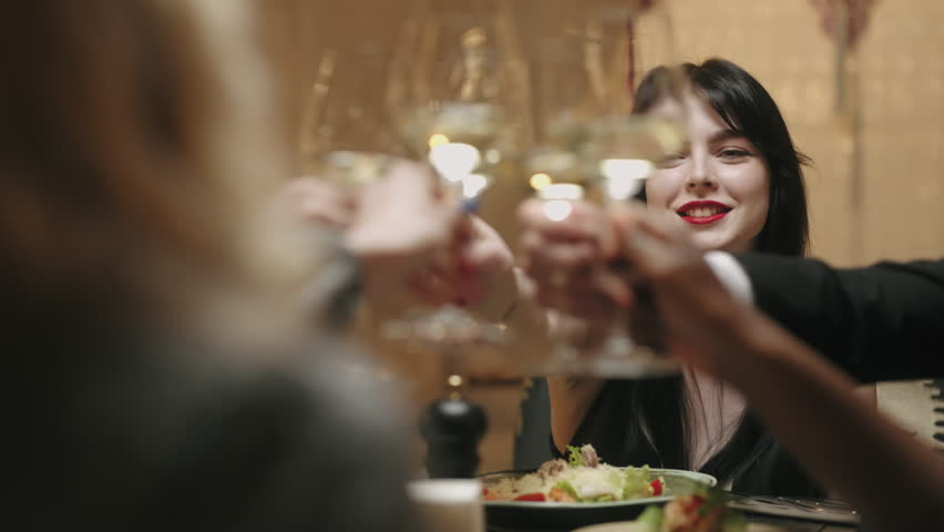 Friends dining in restaurant, clinking glasses with white wine and toasting, celebrating anniversary | Shutterstock HD Video #1098210643