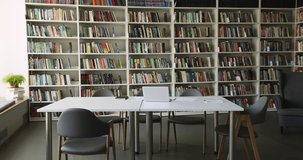 Wall mounted bookshelves with collections of books, periodicals, desk with laptop and copybooks in empty university library. Place for studying, gain new knowledge, get professional skills. Education - Powered by Shutterstock - Get 15% off with code: PIKWIZARD15
