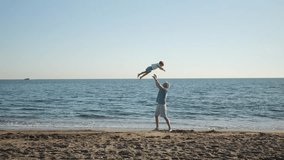 Dad swinging his toddler son into the air on the beach having fun at sunset, father playing with his young son at the beach, priceless parenthood moments, father son silhouette. 4k footage - Powered by Shutterstock - Get 15% off with code: PIKWIZARD15