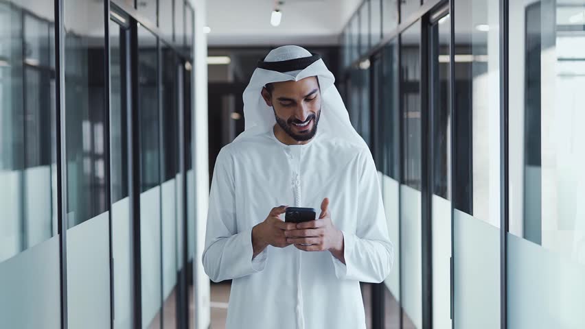 handsome man with dish dasha working in his business office of Dubai. Portraits of a successful businessman in traditional emirates white dress. Concept about middle eastern cultures Royalty-Free Stock Footage #1098218375