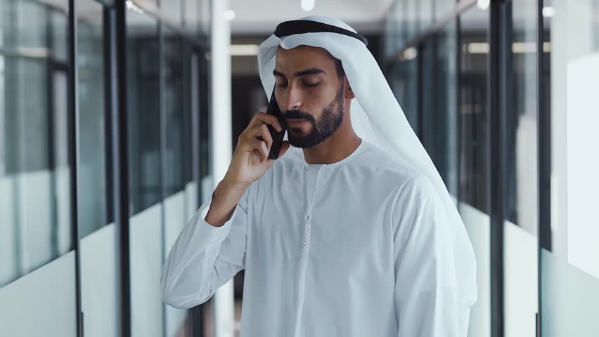 handsome man with dish dasha working in his business office of Dubai. Portraits of a successful businessman in traditional emirates white dress. Concept about middle eastern cultures Royalty-Free Stock Footage #1098218393