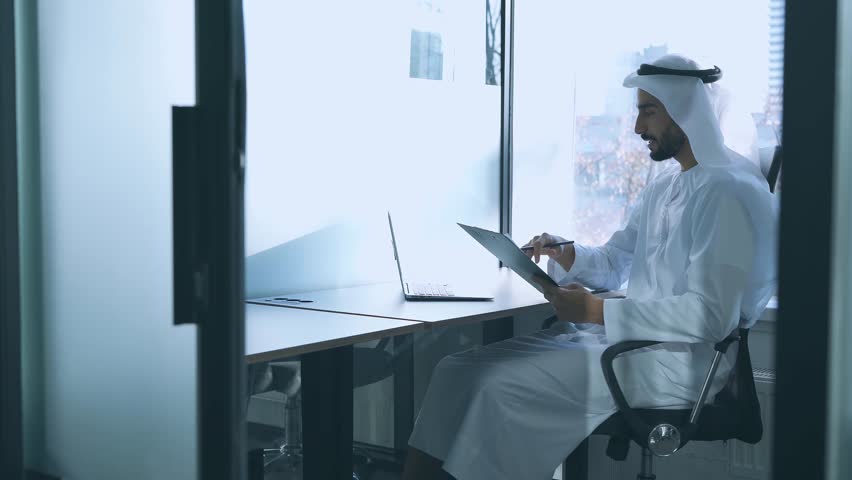 handsome man with dish dasha working in his business office of Dubai. Portraits of a successful businessman in traditional emirates white dress. Concept about middle eastern cultures Royalty-Free Stock Footage #1098218397