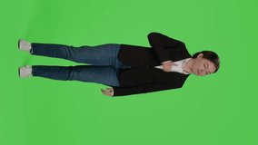 Vertical video: Front view of businesswoman giving thumbs up over green screen studio backdrop, expressing like and approval on camera. Office worker in suit doing okay agreement gesture, acting