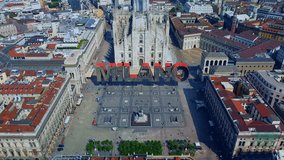 Inscription graphics 3d on video. Milan, fashion, mfw Italy. Rooftops of the city from a bird's eye view. Spiers of Milan Cathedral. Cloudy weather. Colorful text appears and disappears, Aerial view