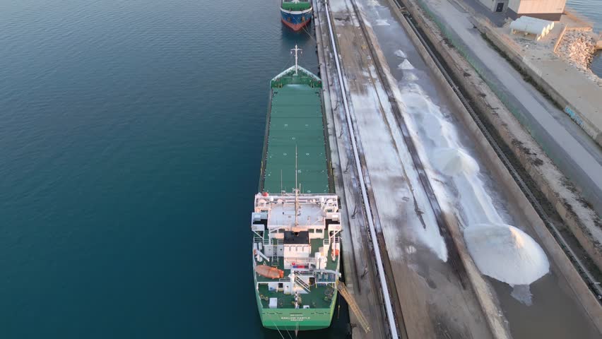 loading salt into a cargo ship for transportation by sea. The ship is loaded with white substance in the port. Salt export. Sea export. Agriculture. Torrevieja, Spain