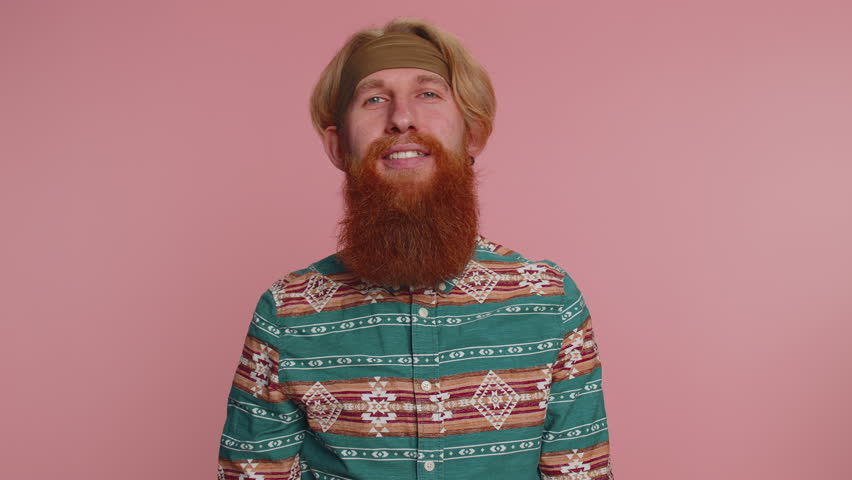 Happy hippie redhead man in pattern shirt shouting, raising fists in gesture I did it, celebrating success, winning, birthday, lottery goal achievemen. Hipster guy boy indoor on pink studio background