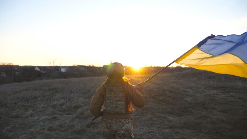 Female ukrainian army soldier runs and waves flag of Ukraine at sunset. Woman in military uniform lifted up flag in honor of the victory against russian aggression. Invasion resistance concept. Slowmo Royalty-Free Stock Footage #1098227125