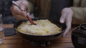 This video shows the hands of a hungry diner scooping a spoon into a hot and steaming Japanese rice bowl.