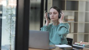 Young businesswoman with black headphones and relaxing sitting at her desk, Relaxation at work concept