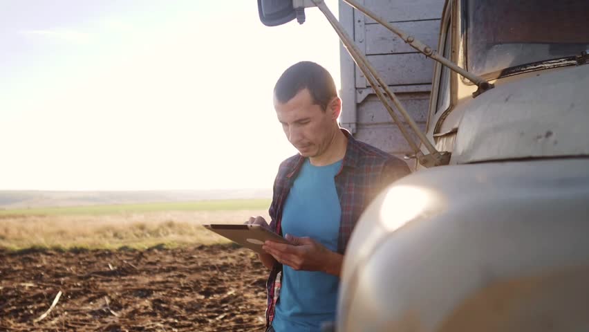 agriculture. farmer driver with digital tablet works next to the car. agriculture business a farming concept. farmer looking at work plan farm on digital tablet Royalty-Free Stock Footage #1098230897
