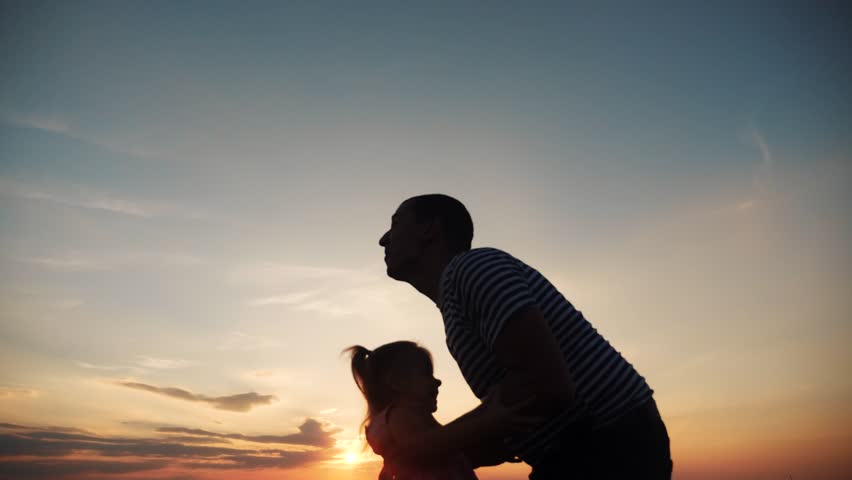 Father and daughter. dad play with his daughter at sunset in the park silhouette throws up. happy family kid dream concept. father and daughter play in the park at dream fun sunset