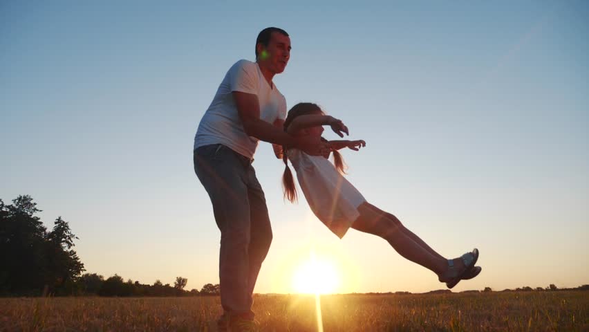 Dad play turn circling his daughter by the arms in the park silhouette at sunset. happy family kid dream concept. dad play in the park fun with his daughter at sunset dream having | Shutterstock HD Video #1098230935