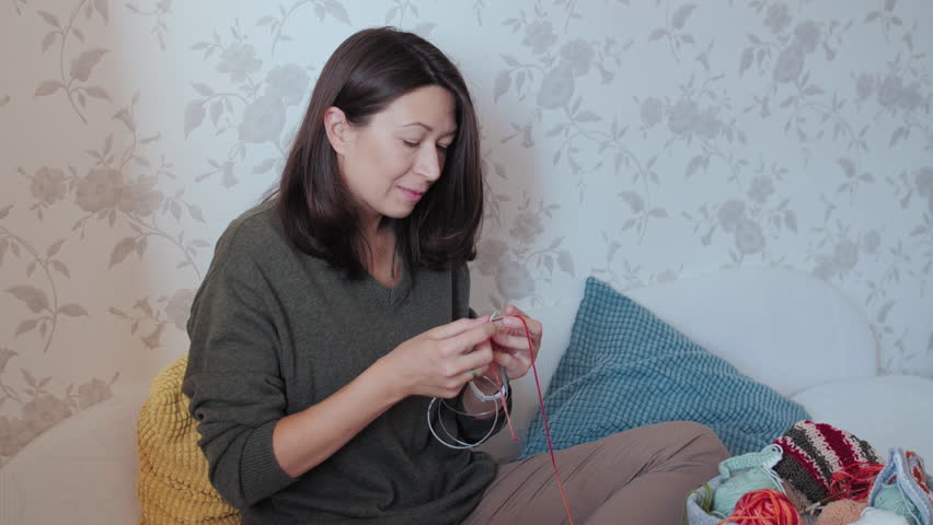 Close-up video of woman knitting something small. Anti-stress hobby. Tranquil leisure at home. Handicraft. Online lessons for amateurs on laptop.