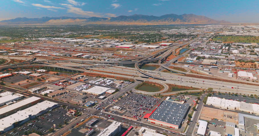 Big parking lots and complicated roads at the outskirts of Salt Lake City. Mountains of Utah at backdrop. Top view.