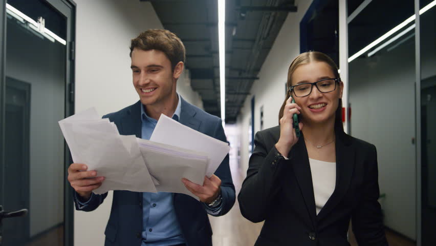 Business team enjoying triumph walking office center. Happy manager talk phone sharing successful results news with executive. Euphoric man throwing papers rejoicing in hall. Corporate victory concept