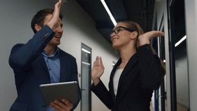 Office employees high five celebrating success. Happy business partners walking hall discussing successful client meeting results. Smiling man use tablet check online report. Company teamwork concept - Powered by Shutterstock - Get 15% off with code: PIKWIZARD15