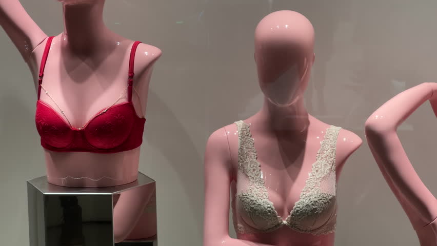 Female mannequins in lace lingerie stand in the window of a lingerie store. View through the glass