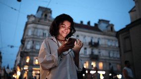 Smiling woman using smartphone on street with night city lights on background - Powered by Shutterstock - Get 15% off with code: PIKWIZARD15