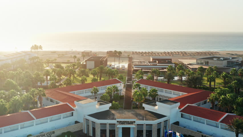Cinematic shot of beach Resort during Golden Hour. Drone shot flying towards the empty beach before sunset.
Soft warm sunshine.
Santa Maria in Sal - Cape Verde. Royalty-Free Stock Footage #1098242077