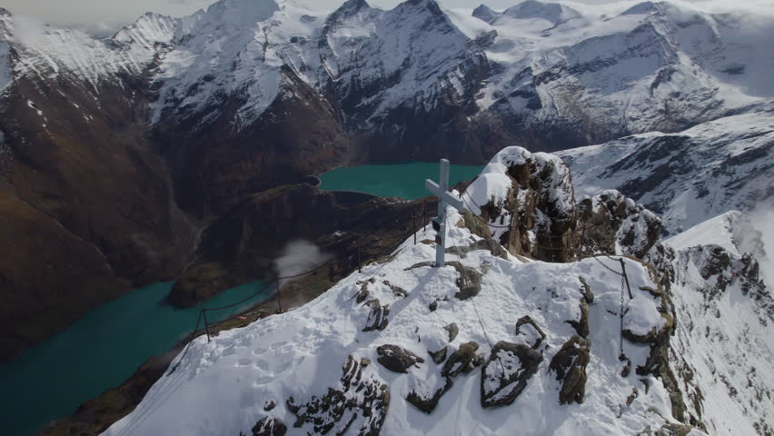 Aerial birds eye shot of cross on summit with green lake in valley in winter - Zell am See,Austria