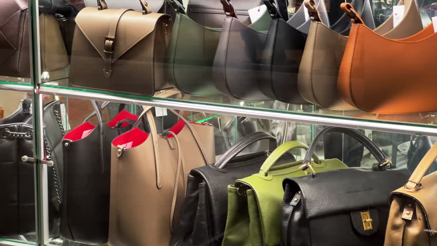 Women's leather handbags stand on the accessories store glass shelves Royalty-Free Stock Footage #1098244017
