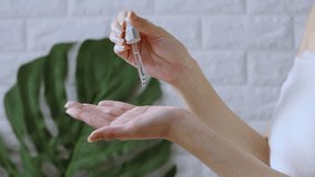 Asian woman applying by dropping essential oil on hand for spa ans skin care. 4K video beauty and spa treatment concept.