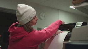 the girl sets the plotter to work so that it cuts out a certain pattern. High quality Full HD video recording