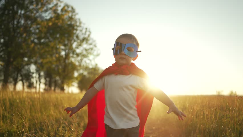 Happy child hero runs on green grass. Boy in a red superhero cape outdoors in park. Child winner path to success.Joy and fun in boy in park.Child Game.Power superhero happy kid.Happy childhood concept | Shutterstock HD Video #1098251621