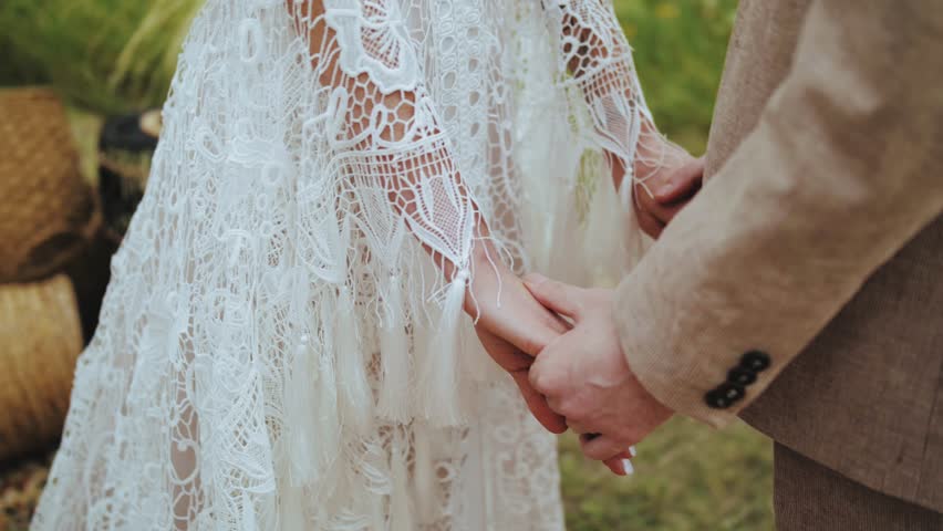 Bride and Groom Holding Hands at the wedding boho style ceremony. close-up holding hands, slow motion shot.