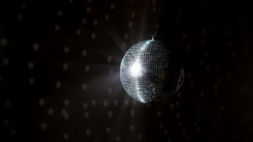 Disco Ball with Reflected Moving Rays Rotating. Mirror disco ball in white light. Isolated disco ball on black background. Close-up. Mirror ball spinning indoors. Performance. The reflection of lights