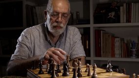 Senior man in glasses playing chess with himself at home. Leisure and entertainment concept. - Powered by Shutterstock - Get 15% off with code: PIKWIZARD15
