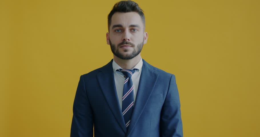 Portrait of bored and annoyed businessman saying bla bla bla and making blabbing hand gesture on yellow background. People and communication concept. | Shutterstock HD Video #1098256803