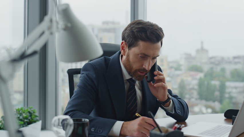 Annoyed business man calling phone sitting work desk closeup. Nervous busy office manager talking smartphone emotionally. Bearded angry ceo director dissatisfied telephone conversation feeling stress. | Shutterstock HD Video #1098268033