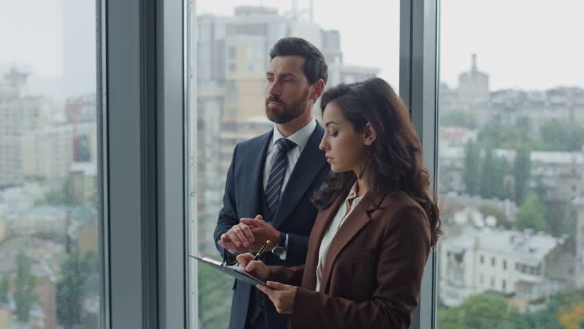 Smart bearded boss telling to girl secretary work issue standing office closeup. Attractive brunette woman assistant holding papers making notes. Middle-aged businessman manager talking with colleague | Shutterstock HD Video #1098268041