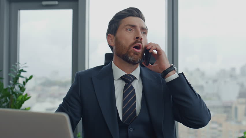 Angry worried businessman calling phone sitting luxury office at work desk closeup. Nervous bearded executive manager discussing company problems on telephone conversation. Man worker feeling stress. | Shutterstock HD Video #1098268205
