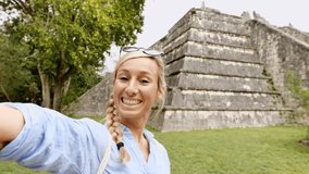 Woman taking selfie video in front of ancient Mayan temple in Mexico.