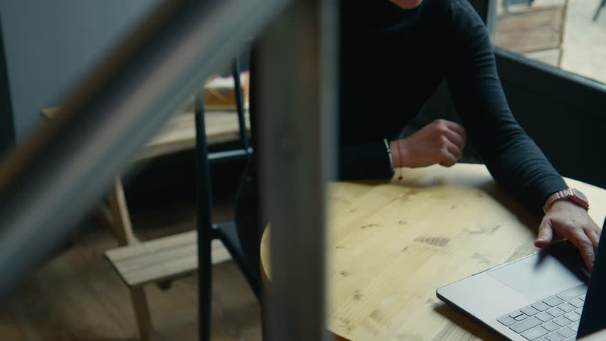 Young business woman work on laptop in specialty coffee shop. Unrecognisable customer at restaurant or cafe, get served lunch by waiter. Customer service in coffeeshop