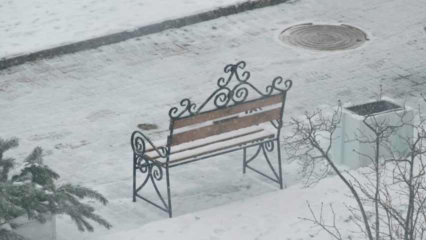 Bench near the house and falling snowflakes