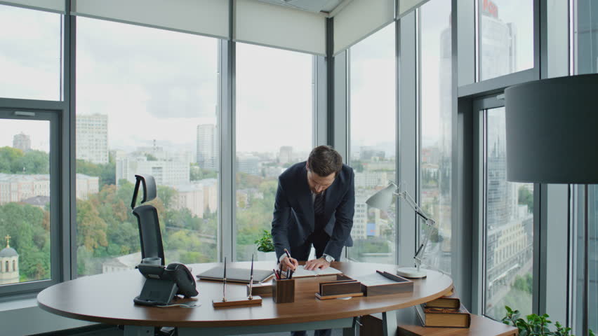 Smart rich businessman thinking about making deal standing in office with crossing hands looking window. Confident investor man signing papers on work table. Ceo manager putting signature on documents | Shutterstock HD Video #1098288591