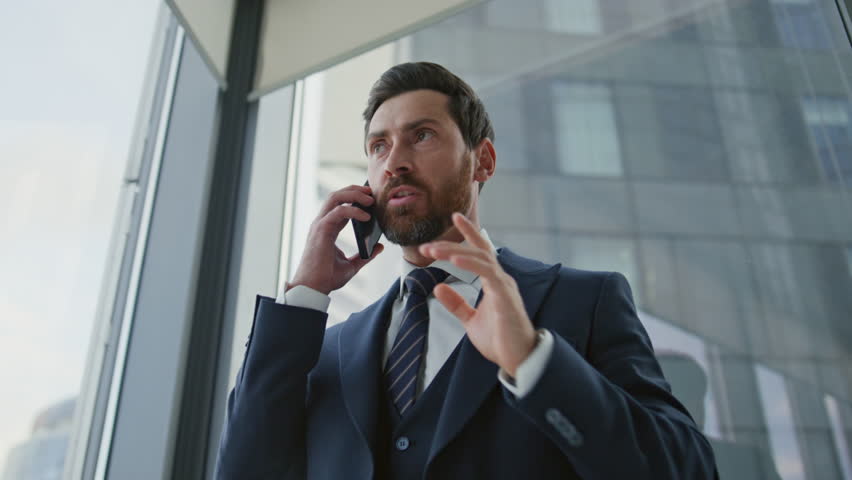 Angry boss shouting arguing in phone call close up. Furious businessman ending conversation standing in modern office. Stressed ceo manager reacting emotionally on bad news company crisis work fail. Royalty-Free Stock Footage #1098288669