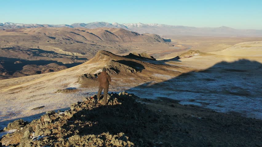 A man stands on the edge of a cliff and looks into the distance. Altai mountains, Siberia
