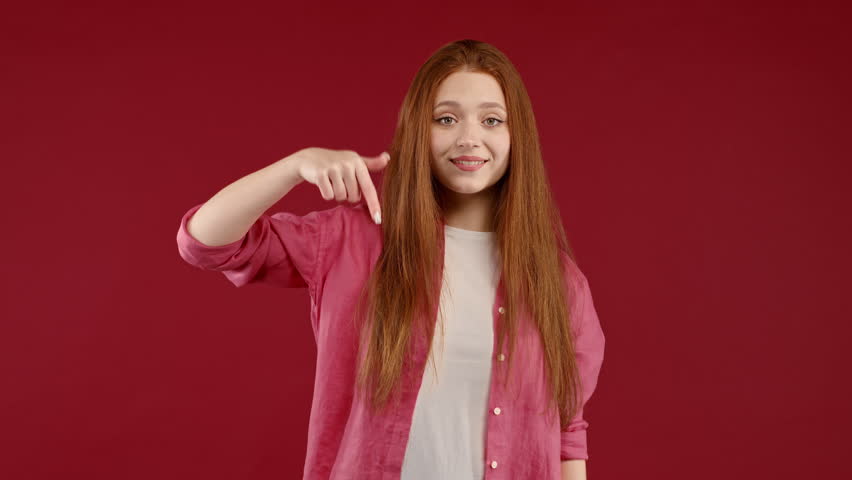 Happy woman pointing down to advertising area. Red background. Young lady asking to click to subscribe below. Copy space for your commercial idea, promotional content. | Shutterstock HD Video #1098293723