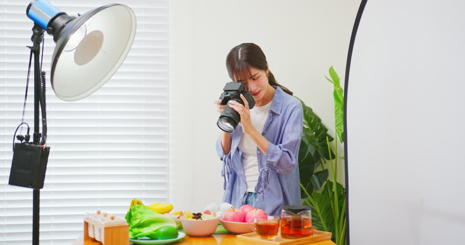 Female Asian photographer taking pictures of healthy food with satisfaction